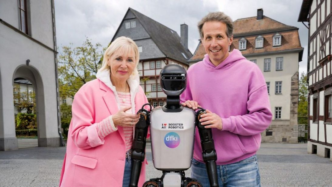 Digitalministerin Dr. Kristina Sinemus und Moderator Willy Weitzel mit einem Roboter