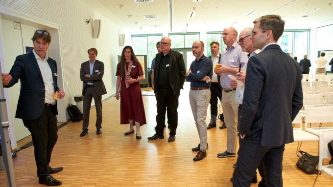 Teilnehmerinnen und Teilnehmer einer Arbeitsgruppe stehen im Kreis um ein Plakat